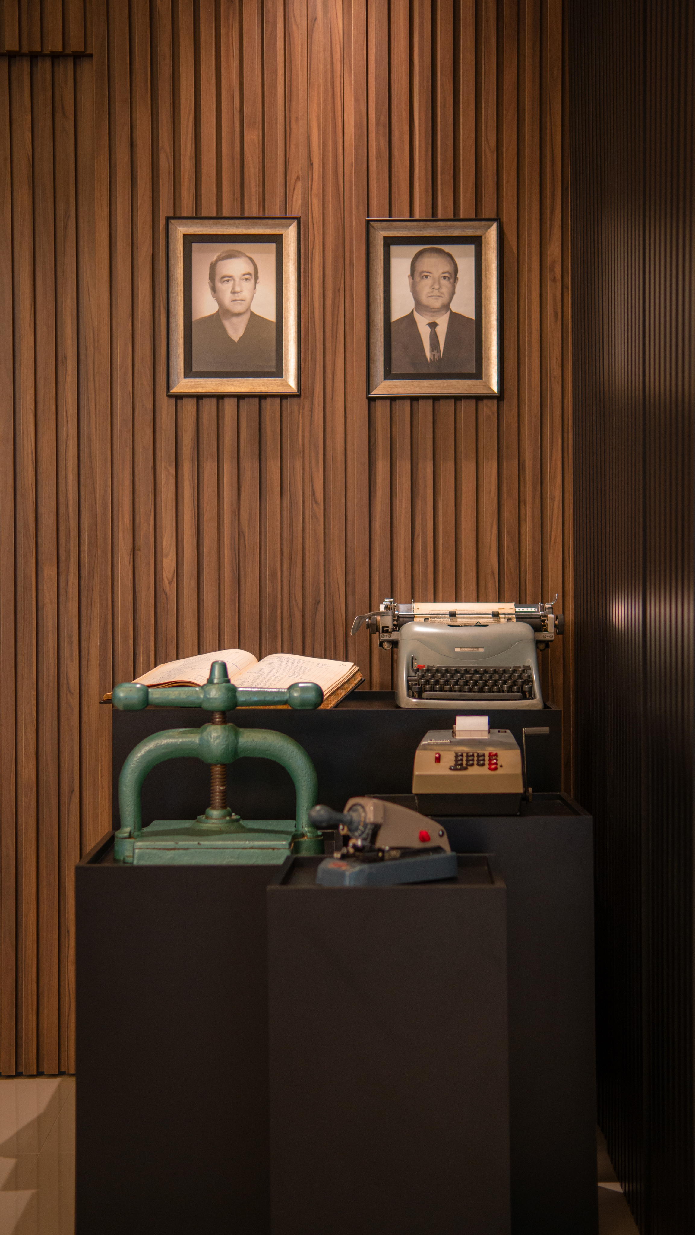 Memória da história da PCE com retratos dos fundadores e equipamentos contábeis